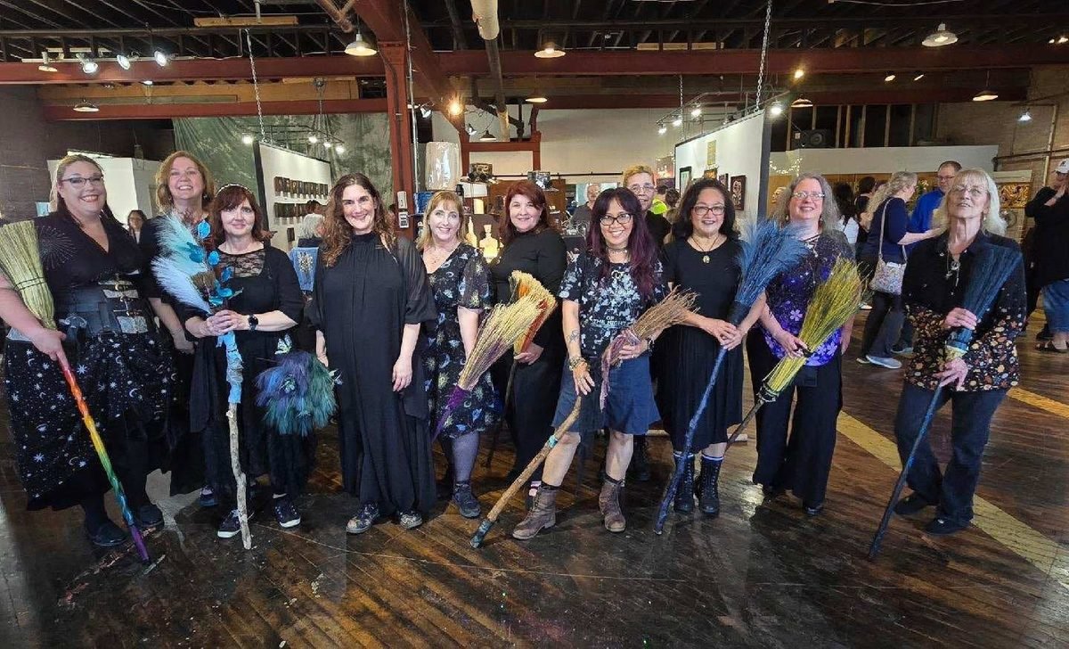 Members of the Forest City Dance Circle in dark seasonal costume, holding decorated brooms and staffs, gathered together at an event space in Rockford, Illinois.